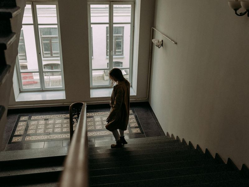 A person performing a controlled lunge in a bright, spacious room with natural light.